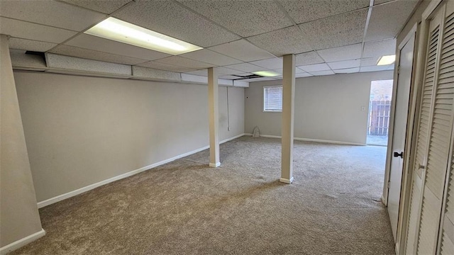 basement featuring carpet flooring, a drop ceiling, and baseboards