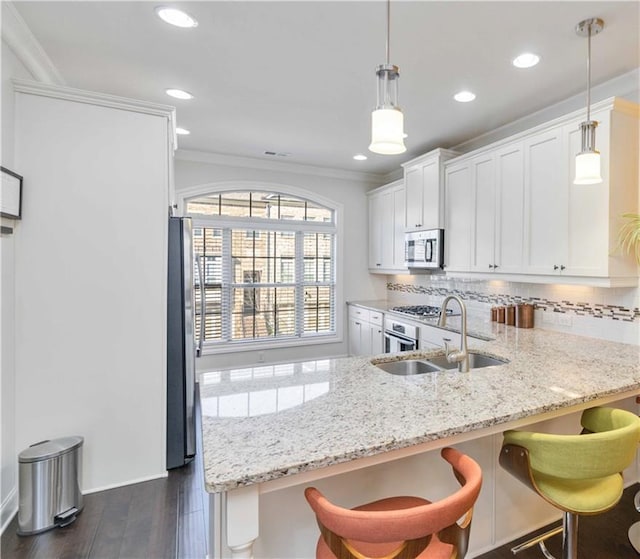 kitchen featuring appliances with stainless steel finishes, dark wood-type flooring, sink, decorative light fixtures, and white cabinetry