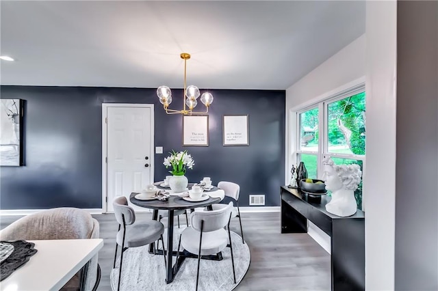 dining room featuring visible vents, baseboards, wood finished floors, and a notable chandelier