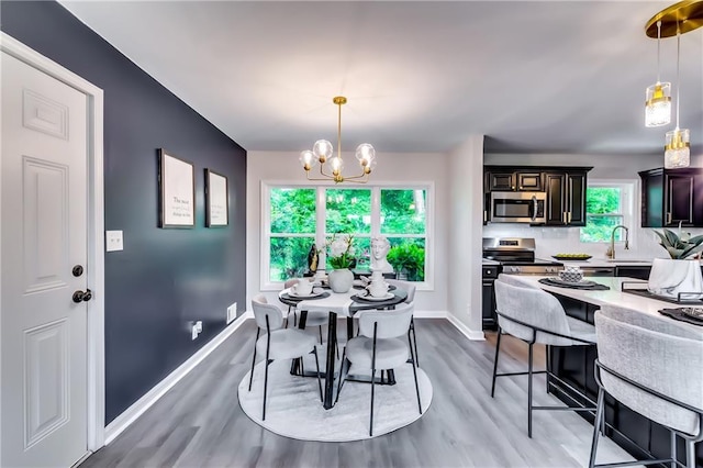 dining area featuring baseboards, light wood-style flooring, and a notable chandelier