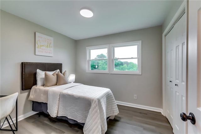 bedroom with dark wood-style flooring, baseboards, and a closet