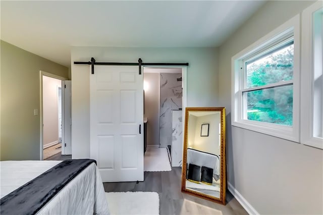 unfurnished bedroom featuring baseboards, a barn door, and wood finished floors