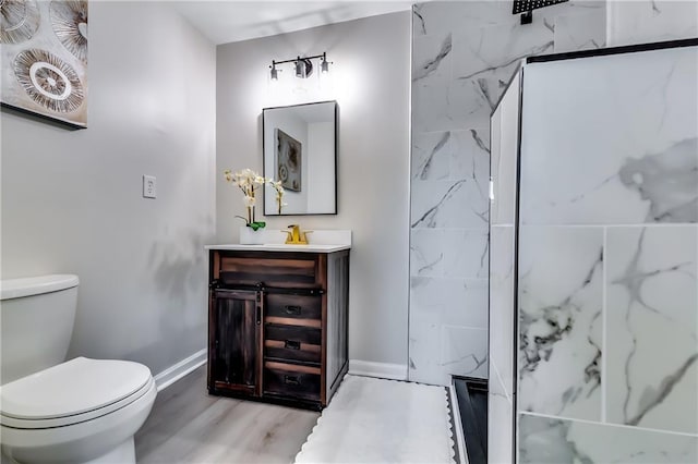 bathroom featuring toilet, baseboards, wood finished floors, and vanity