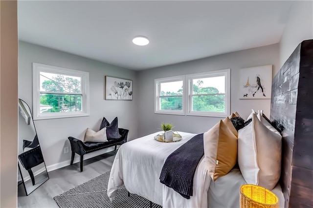 bedroom with baseboards, light wood-style flooring, and multiple windows