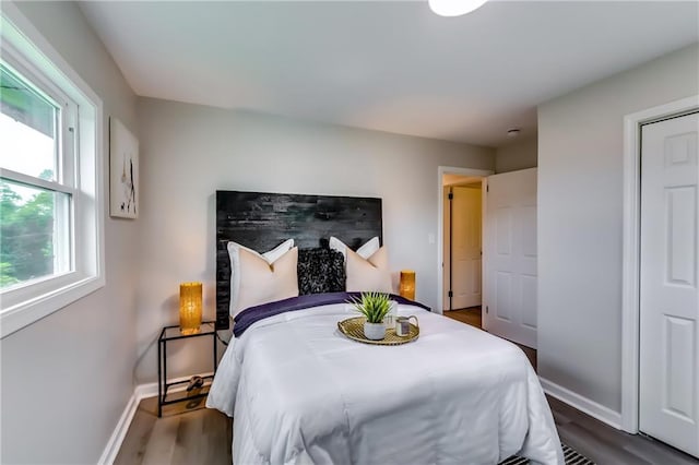 bedroom with dark wood-type flooring and baseboards