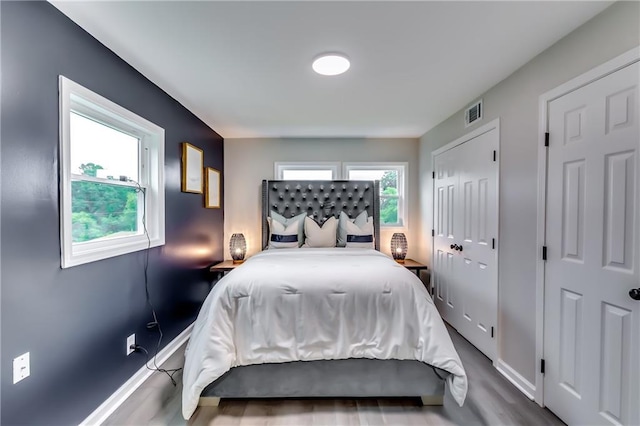 bedroom featuring baseboards, visible vents, and wood finished floors