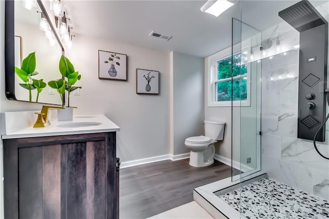 full bathroom with vanity, toilet, a marble finish shower, baseboards, and visible vents