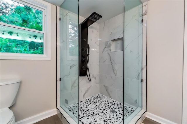 full bathroom featuring baseboards, a marble finish shower, and toilet