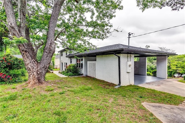 view of home's exterior with concrete driveway, a yard, an attached carport, and stucco siding