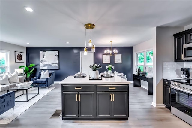 kitchen featuring pendant lighting, appliances with stainless steel finishes, light countertops, open floor plan, and an inviting chandelier
