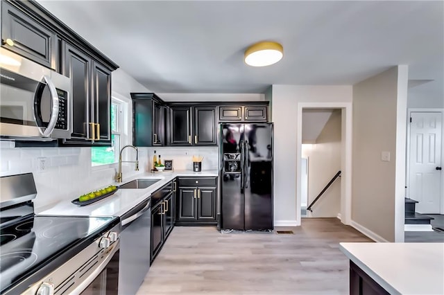 kitchen featuring stainless steel appliances, light wood-style floors, a sink, and tasteful backsplash
