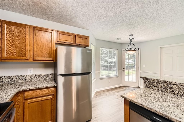 230 Belmont Trl, Covington, GA 30016 - kitchen featuring appliances with stainless steel finishes, light wood-style flooring, brown cabinetry, a textured ceiling, and light stone countertops