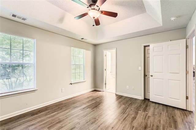 230 Belmont Trl, Covington, GA 30016 - unfurnished bedroom featuring wood finished floors, a raised ceiling, ensuite bath, a textured ceiling, and a ceiling fan