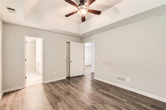 230 Belmont Trl, Covington, GA 30016 - unfurnished bedroom with a tray ceiling, wood finished floors, ensuite bath, and ceiling fan