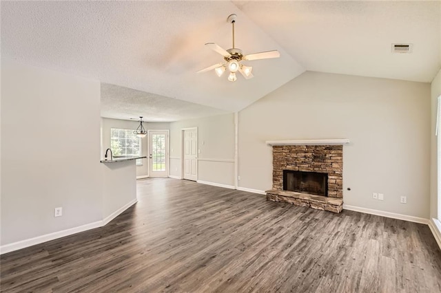 230 Belmont Trl, Covington, GA 30016 - unfurnished living room featuring ceiling fan, dark wood finished floors, a stone fireplace, vaulted ceiling, and a textured ceiling