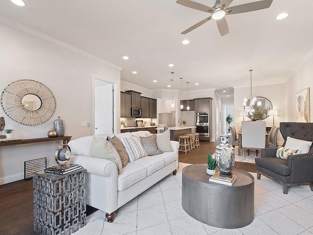 living room with crown molding, dark hardwood / wood-style floors, and ceiling fan with notable chandelier