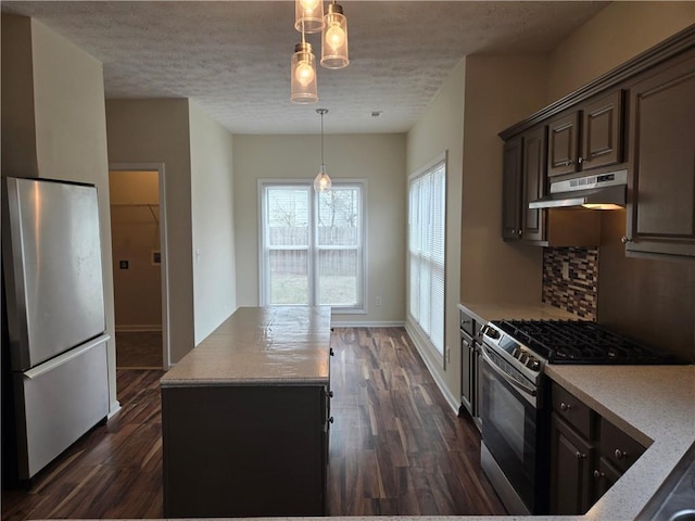 kitchen featuring dark brown cabinets, hanging light fixtures, dark hardwood / wood-style floors, stainless steel appliances, and decorative backsplash