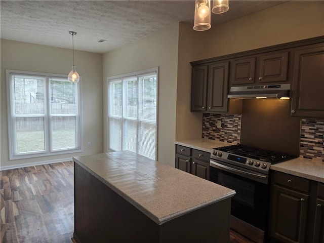 kitchen with dark brown cabinetry, stainless steel gas range, tasteful backsplash, decorative light fixtures, and a center island