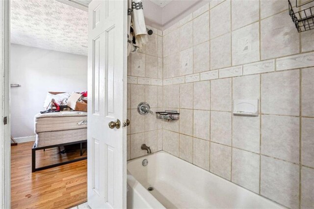 270 Oak Ridge Rd, Covington, GA 30016 - bathroom featuring shower / bathing tub combination, baseboards, wood finished floors, and a textured ceiling