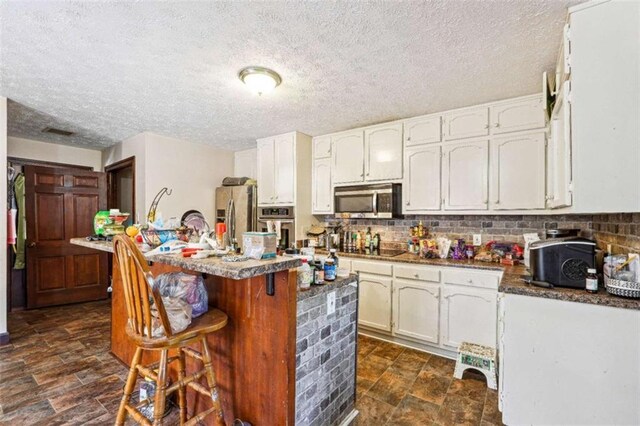 270 Oak Ridge Rd, Covington, GA 30016 - kitchen with white cabinetry, a kitchen bar, stainless steel appliances, backsplash, and a kitchen island