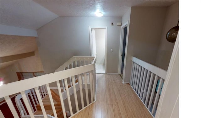 corridor with hardwood / wood-style flooring, a textured ceiling, and lofted ceiling