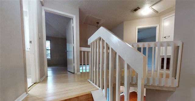 stairs featuring a textured ceiling and wood-type flooring