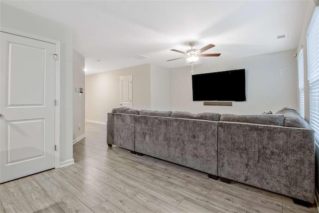 living area featuring visible vents, light wood-style flooring, baseboards, and a ceiling fan