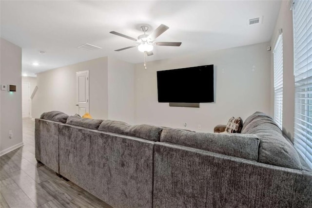 living area featuring visible vents, baseboards, ceiling fan, and wood finished floors