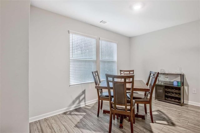 dining space with wood finished floors, visible vents, and baseboards