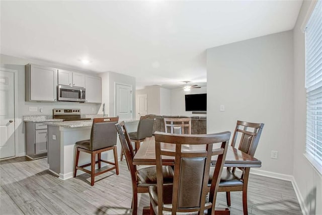 dining space featuring light wood-type flooring, baseboards, and ceiling fan