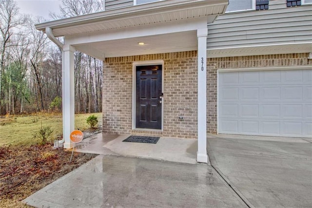 doorway to property featuring brick siding and concrete driveway