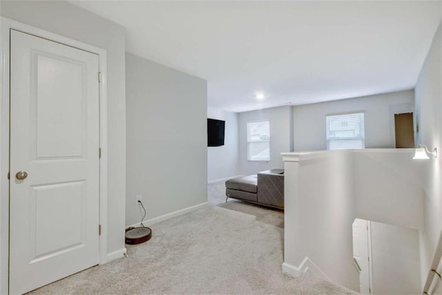 hallway with an upstairs landing, baseboards, and carpet floors