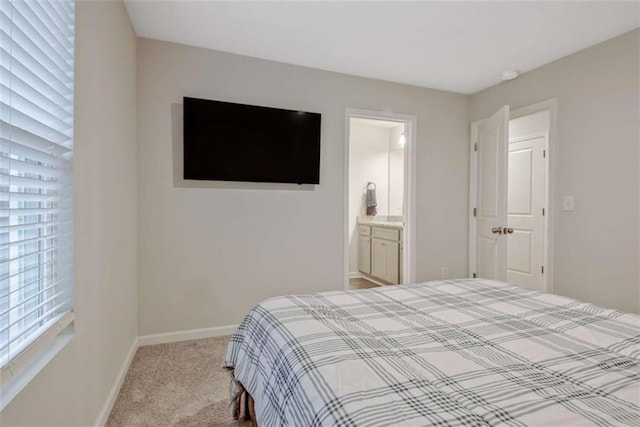 bedroom featuring light colored carpet, ensuite bath, and baseboards