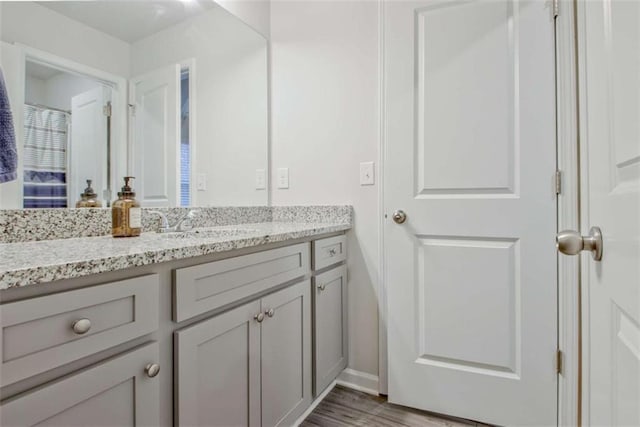 bathroom with baseboards, wood finished floors, and vanity