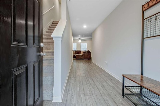 hall featuring baseboards, stairs, and light wood-style floors