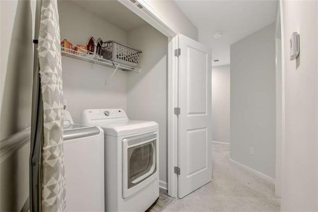 laundry area with baseboards, independent washer and dryer, laundry area, and light carpet