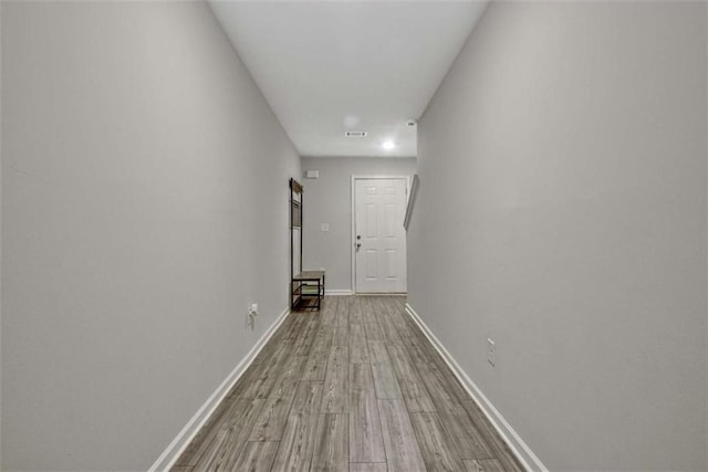 hall with visible vents, baseboards, and wood finished floors