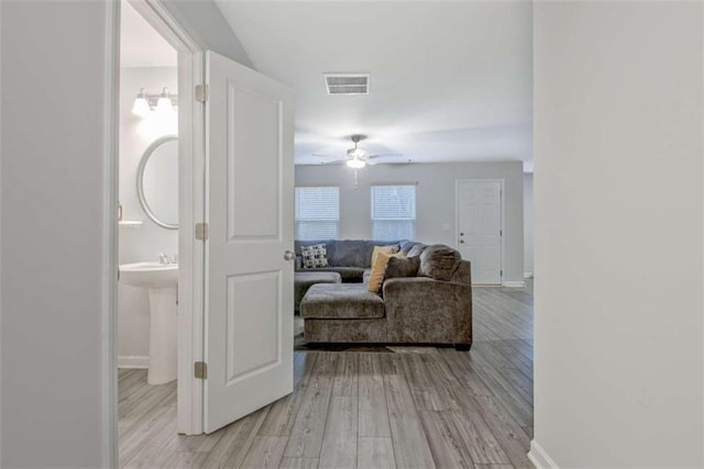 hallway with visible vents, baseboards, and light wood-style floors