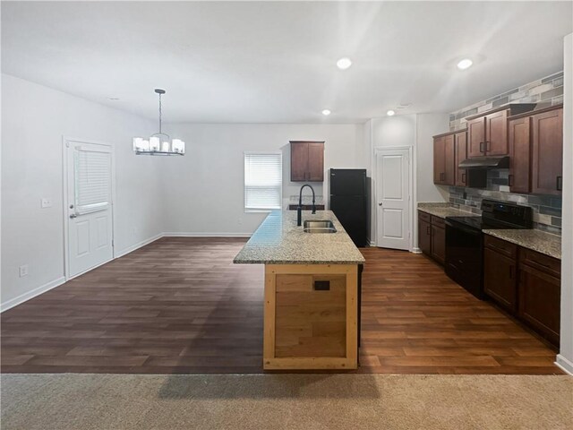 kitchen featuring hanging light fixtures, sink, a center island with sink, dark wood-type flooring, and black appliances