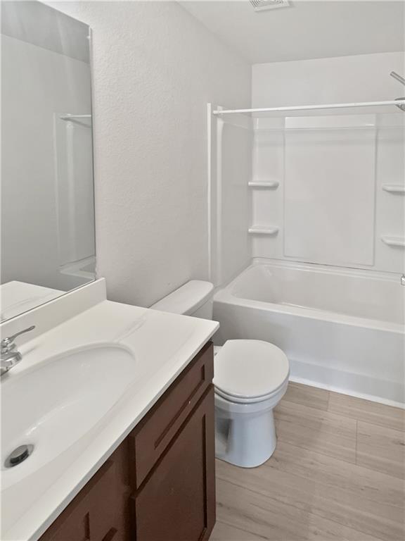 full bathroom with tub / shower combination, vanity, toilet, and hardwood / wood-style floors