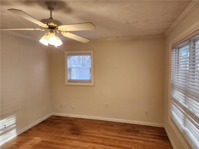 spare room featuring baseboards, ornamental molding, ceiling fan, and wood finished floors