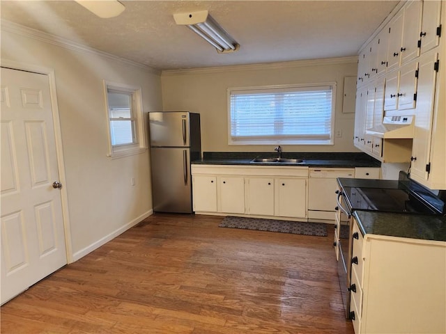 kitchen featuring stainless steel appliances, dark countertops, a sink, and wood finished floors