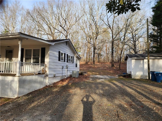 view of property exterior with cooling unit, covered porch, and an outdoor structure