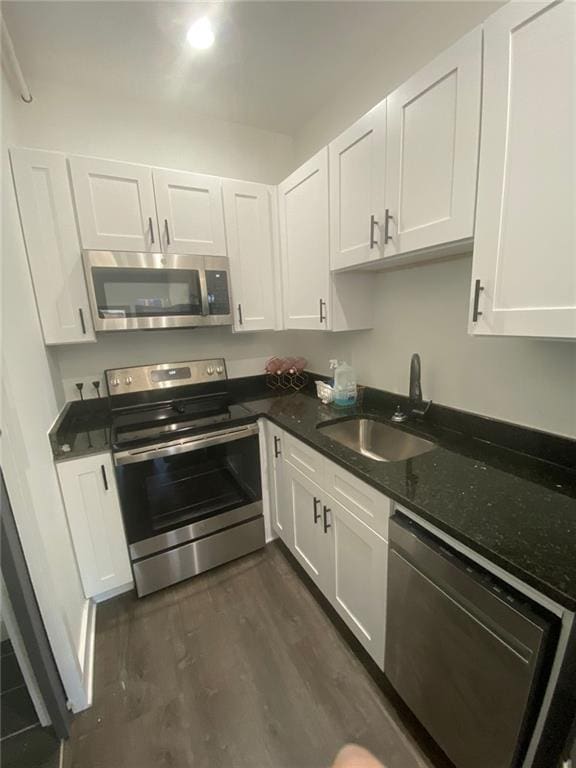 kitchen featuring dark wood-type flooring, dark stone counters, sink, white cabinetry, and stainless steel appliances