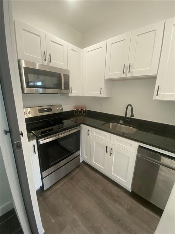 kitchen featuring dark hardwood / wood-style flooring, white cabinetry, sink, and appliances with stainless steel finishes