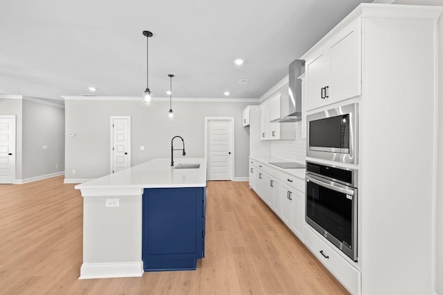 kitchen with wall chimney exhaust hood, decorative light fixtures, stainless steel appliances, sink, and a center island with sink