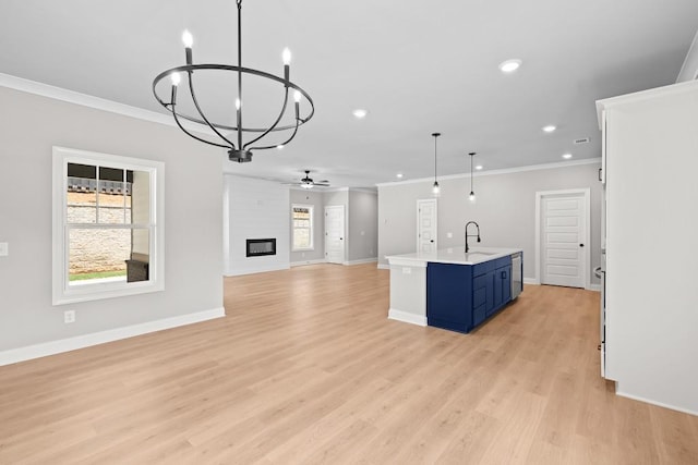 kitchen with decorative light fixtures, blue cabinetry, a large fireplace, sink, and a center island with sink