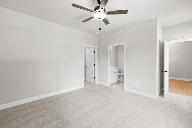 unfurnished bedroom featuring ceiling fan, light colored carpet, and ensuite bath