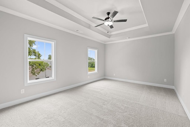 carpeted spare room with ceiling fan, a tray ceiling, and crown molding