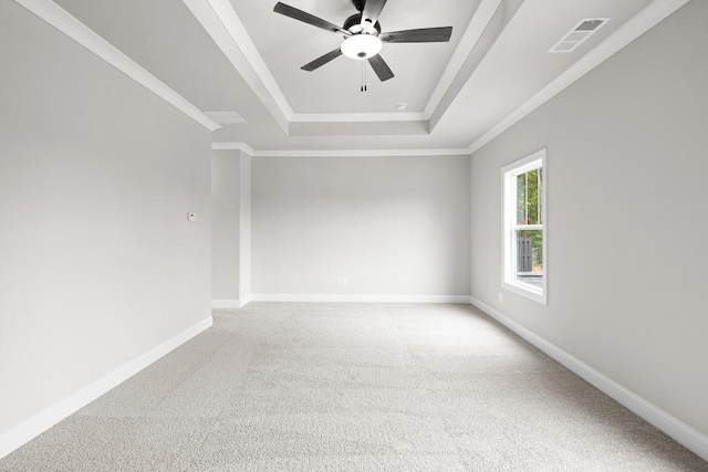 carpeted spare room with ceiling fan, a tray ceiling, and crown molding